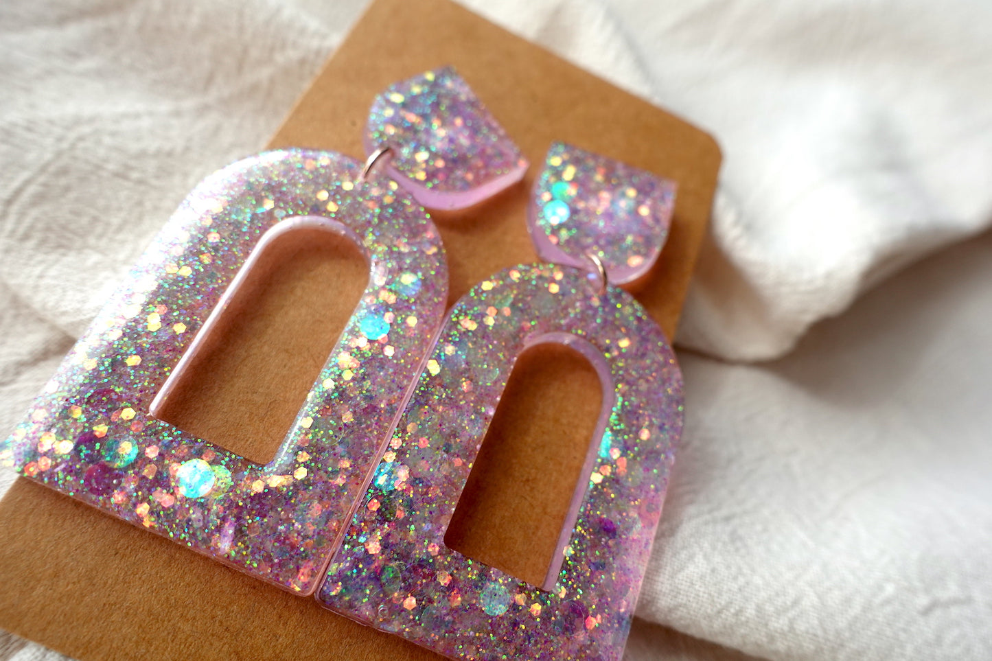 Boog oorbellen doorzichtig lichtroze met glitter - statement oorbellen
