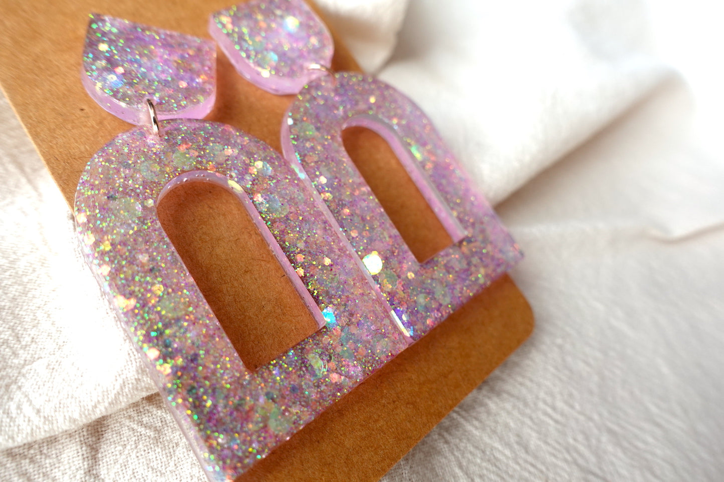 Boog oorbellen doorzichtig lichtroze met glitter - statement oorbellen