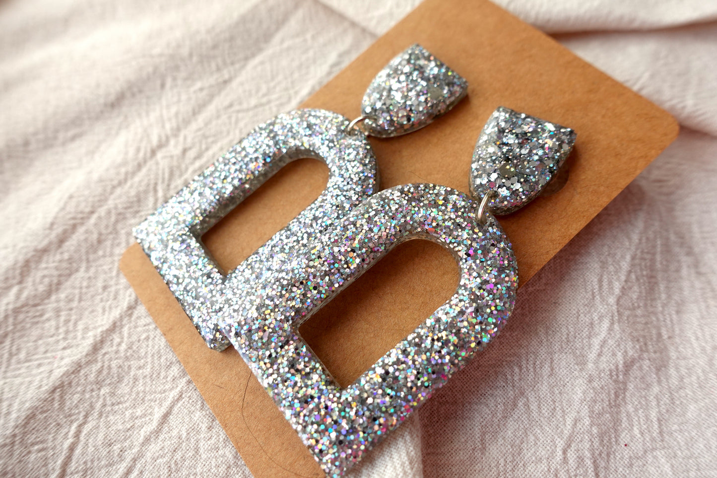 Boog oorbellen (zilveren holografische glitter)